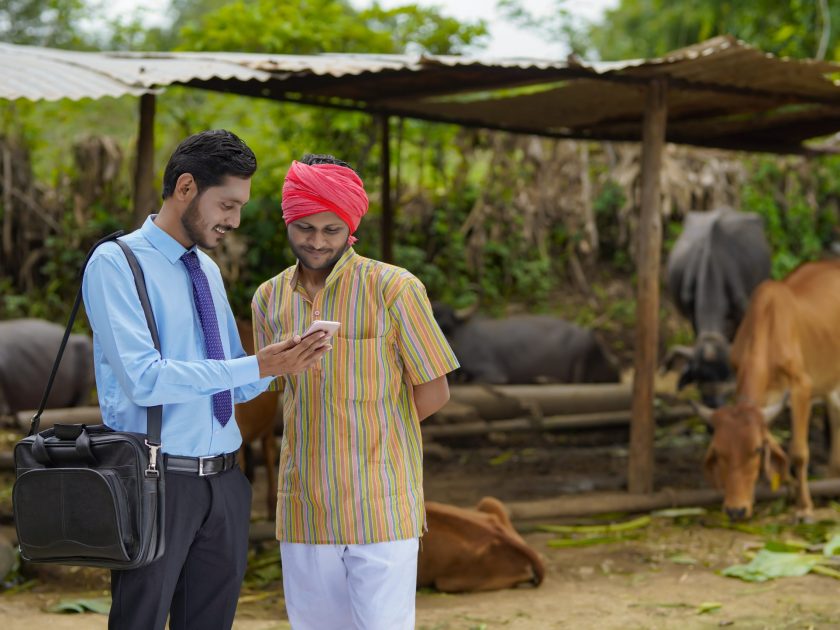 Young agronomist showing some detail to farmer in smartphone.