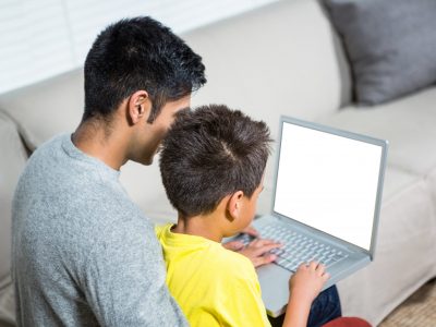 Father and son using laptop on the sofa in living room